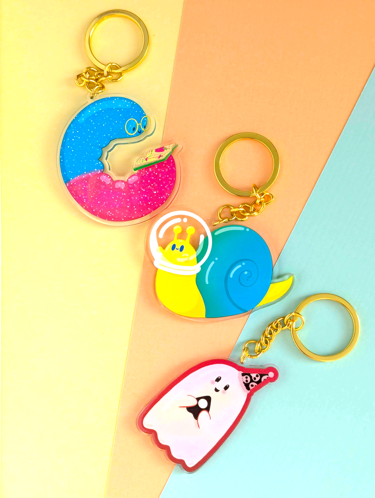 Three colorful keychains on a two-tone yellow and blue background