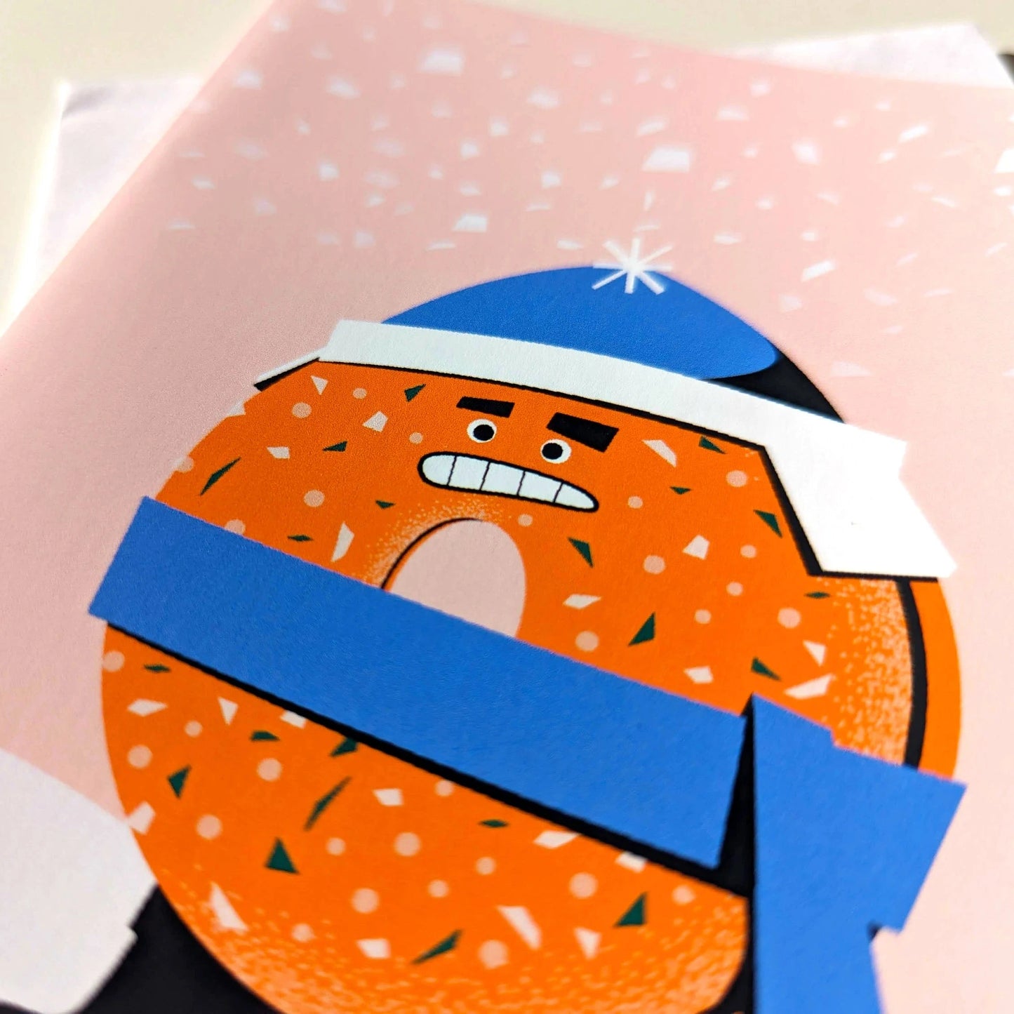 Cartoon donut character with a blue scarf on a pink background
