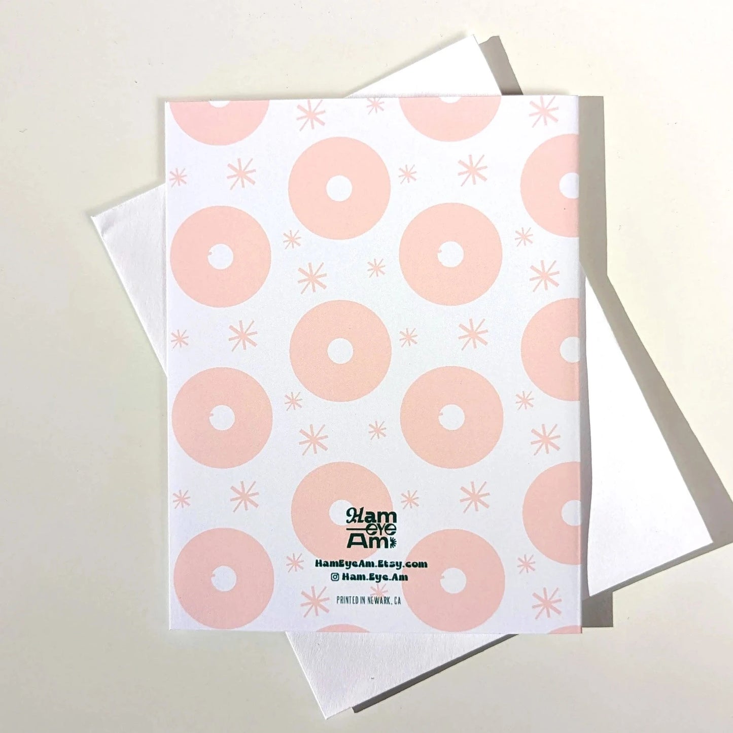 Card with pink donut pattern and visible brand name on a light gray background
