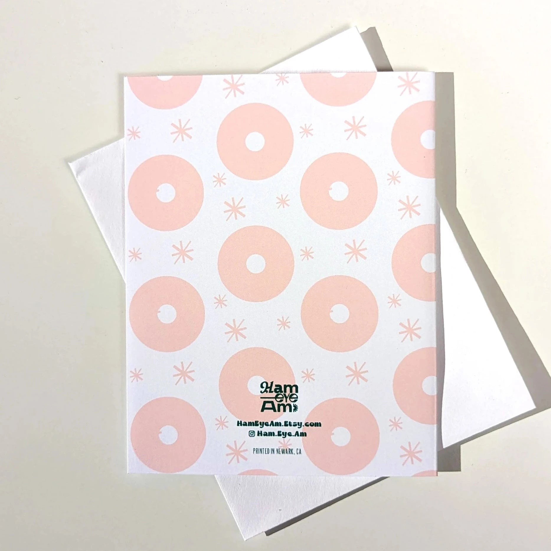 Card with pink donut pattern and visible brand name on a light gray background